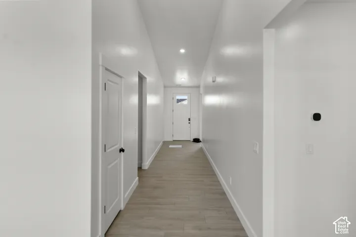 Entry hallway featuring wood-finish flooring, recessed lighting, and crisp white walls