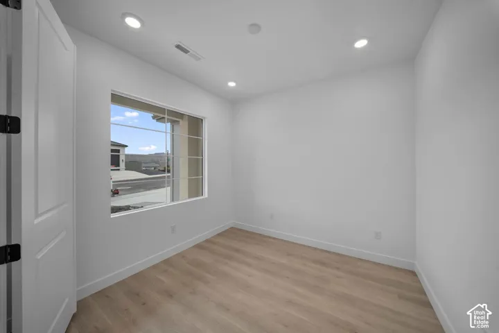 Recessed ceiling lighting, wood-finish flooring, white trim, and a window with grid detailing