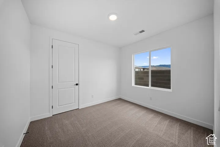 Carpeted flooring, white interior door with dark hardware, white walls, and a window with a mountain backdrop