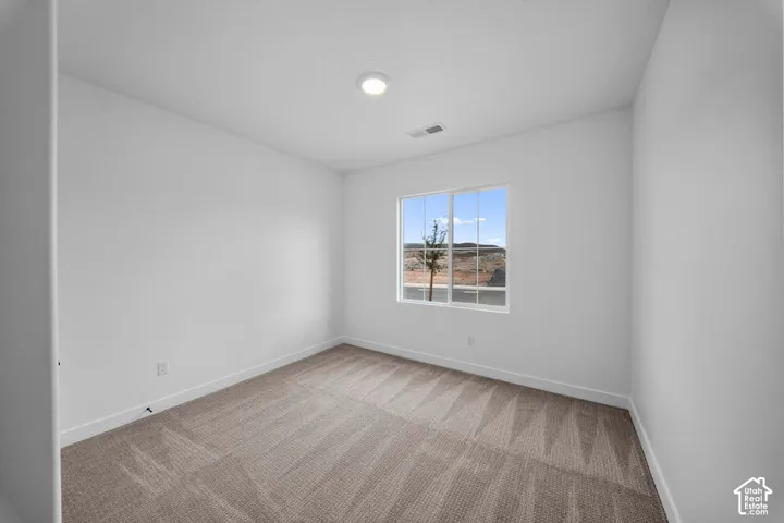 Recessed ceiling light, neutral-toned walls, patterned carpet, and a white-framed window