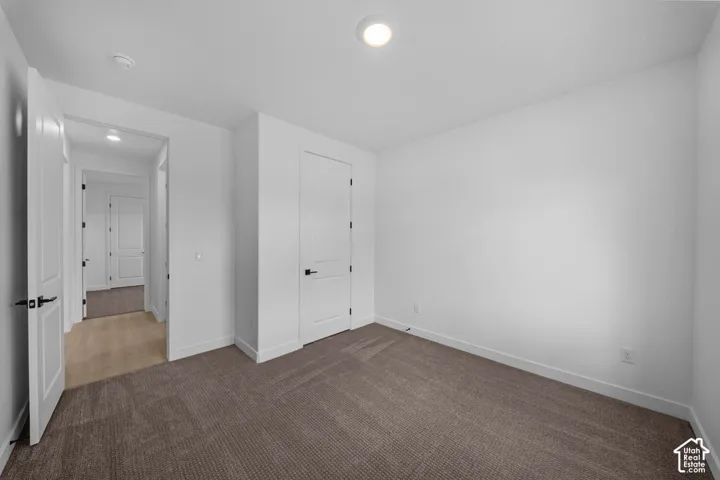 Neutral wall color, recessed ceiling lighting, modern interior doors with black hardware, and carpet flooring