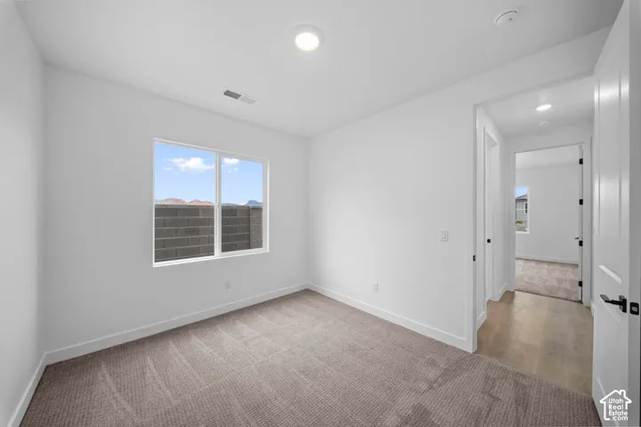 Recessed ceiling lighting, white interior doors with black hardware, carpeted flooring, and a large window