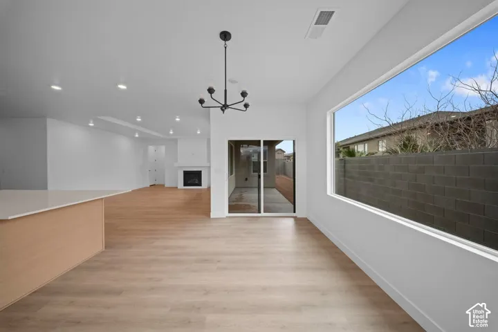 Recessed lighting, wood-finish flooring, built-in fireplace, sliding glass door, and a large picture window