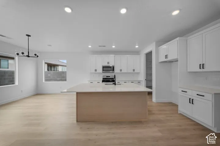 Open concept living area featuring wood-finish flooring, white cabinetry, a kitchen island with stone countertop, and recessed lighting