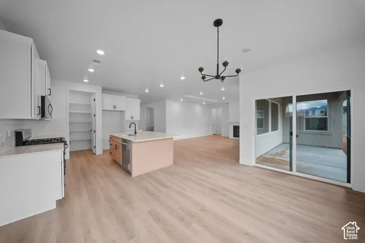 Open-concept living space with wood-finish flooring, recessed lighting, and a modern chandelier