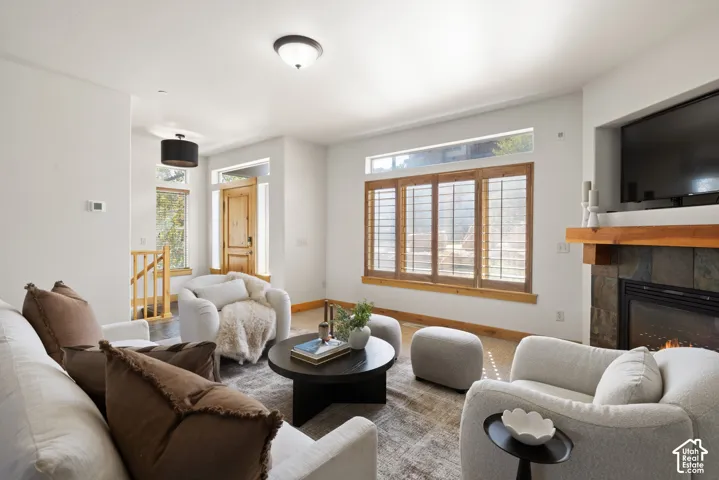 Living area featuring a stone-clad fireplace with wood mantel, wood-finish flooring, and natural wood window shutters