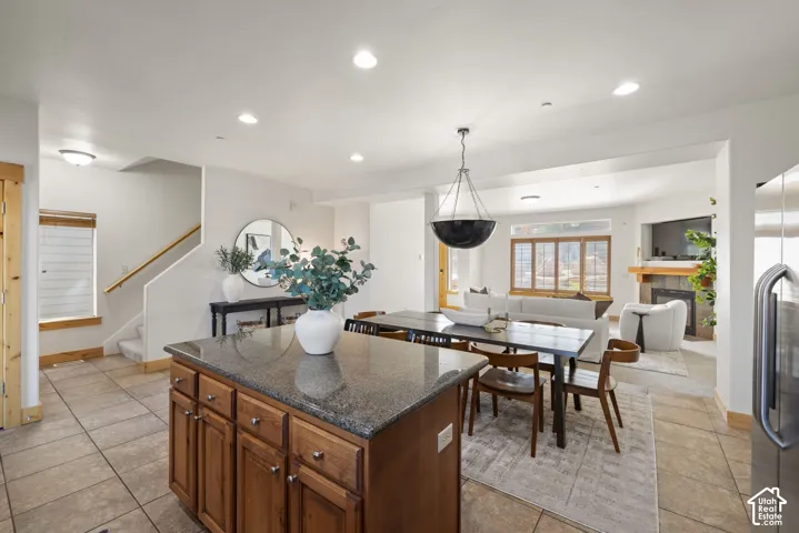 Open concept living space featuring a wood-finish kitchen island with stone countertop, tile flooring, and recessed lighting