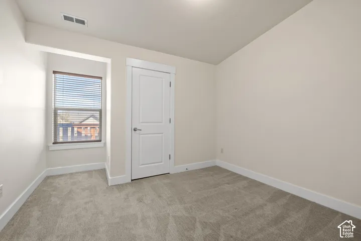 Neutral wall tones, gray carpeting, white trim, and a window with blinds