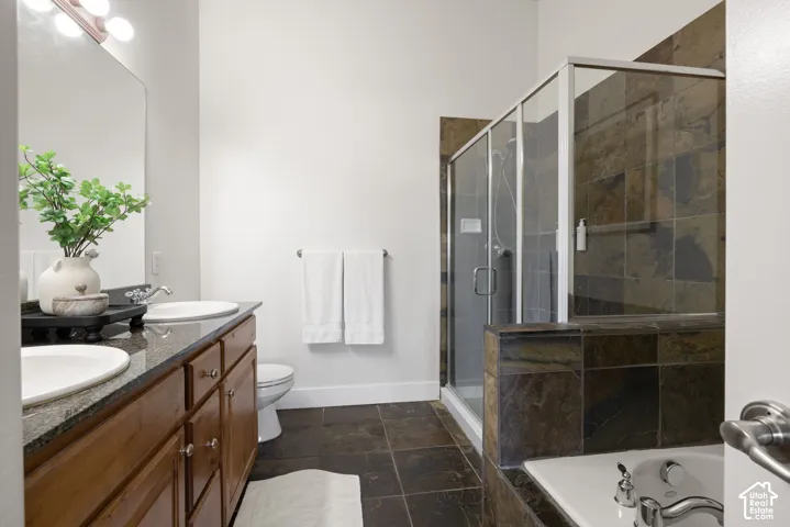 Dual vanity with vessel sinks, dark granite countertop, wood-finish cabinetry, and a large mirror
