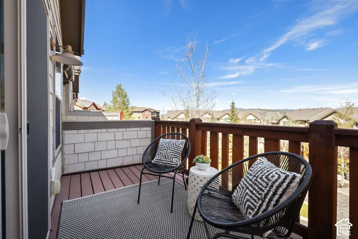 Exterior balcony featuring wood-finish decking, a robust wood railing, and a wall with shingle-style siding