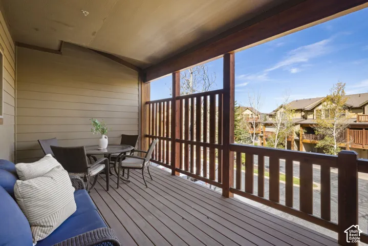 Covered deck with composite wood-finish flooring, vertical wood railings, and expansive windows framing neighborhood scenery