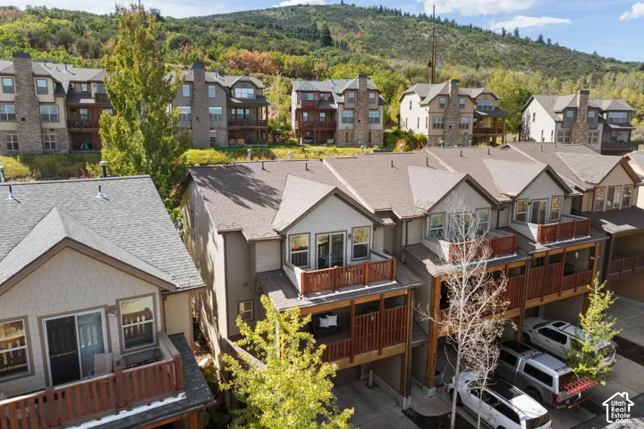 Multi-level townhome featuring multiple balconies with wood railings, a covered carport, and a pitched shingle roof