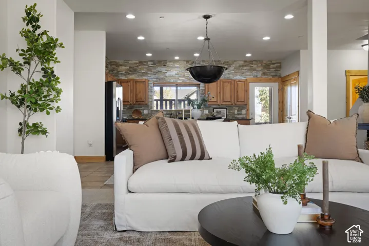 Open-concept living area featuring recessed lighting, a stone accent wall, wood cabinetry, and a black bowl pendant light