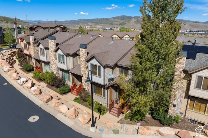 Townhome exterior featuring stone siding accents, wood trim, dark shingle roofing, and solar panels