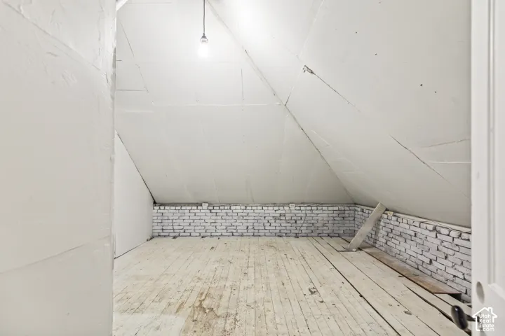 Exposed wood plank flooring and white-painted brick wall