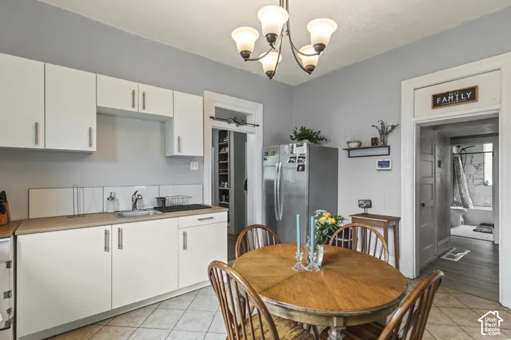 Kitchen featuring white cabinetry with silver hardware, a stainless steel sink, and light-toned countertops