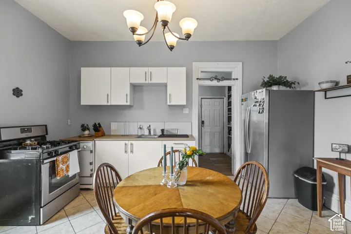 Kitchen featuring white cabinetry, light wood-finish countertops, stainless steel appliances, and tile flooring