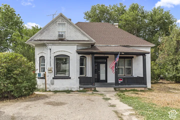 White brick exterior with a dark-trimmed covered porch and a prominent gabled dormer featuring decorative shingles