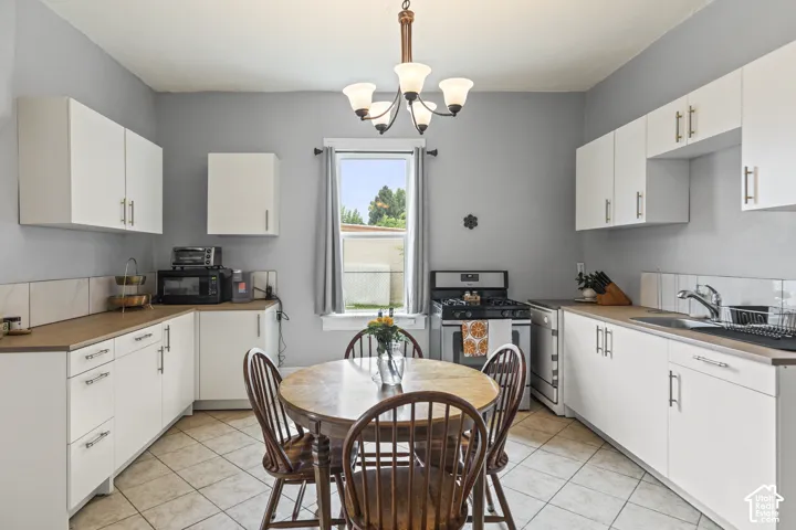 Kitchen featuring extensive white cabinetry, wood-finish countertops, tile flooring, and a gas range