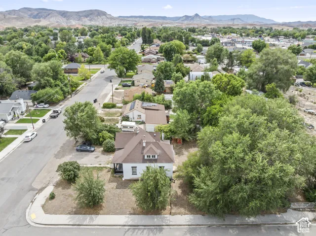 Corner lot property with a gabled roof and dormer window, surrounded by mature trees