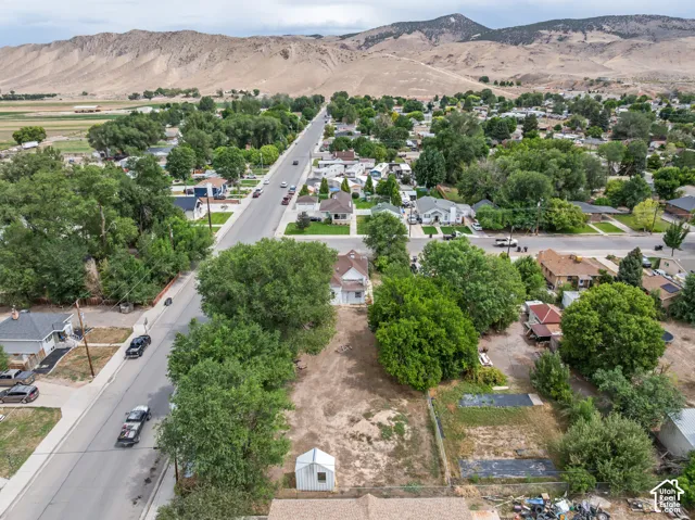 Expansive lot with distant mountain terrain, mature trees, and street access