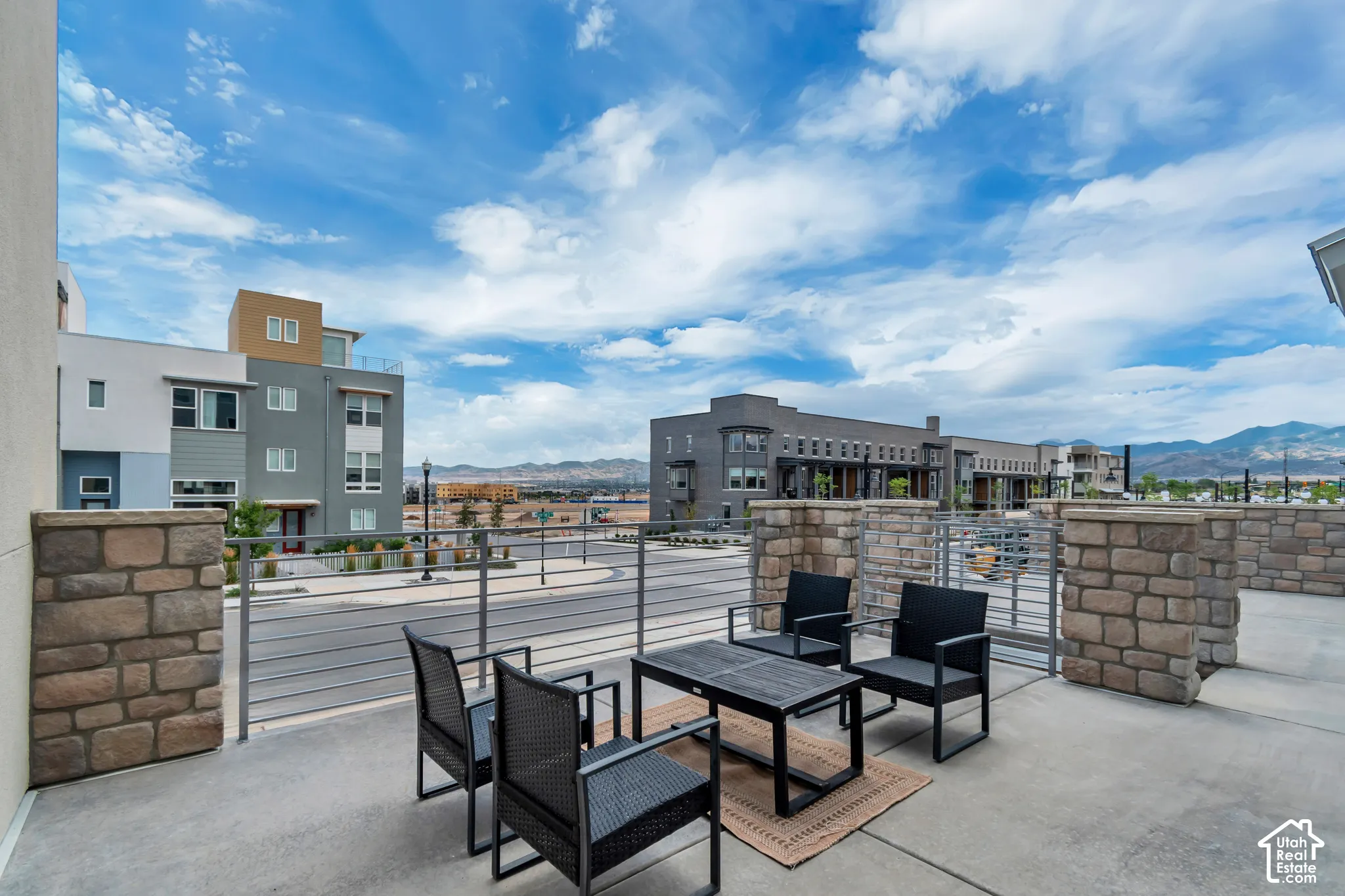 Paved outdoor patio featuring stone-clad walls and metal railing
