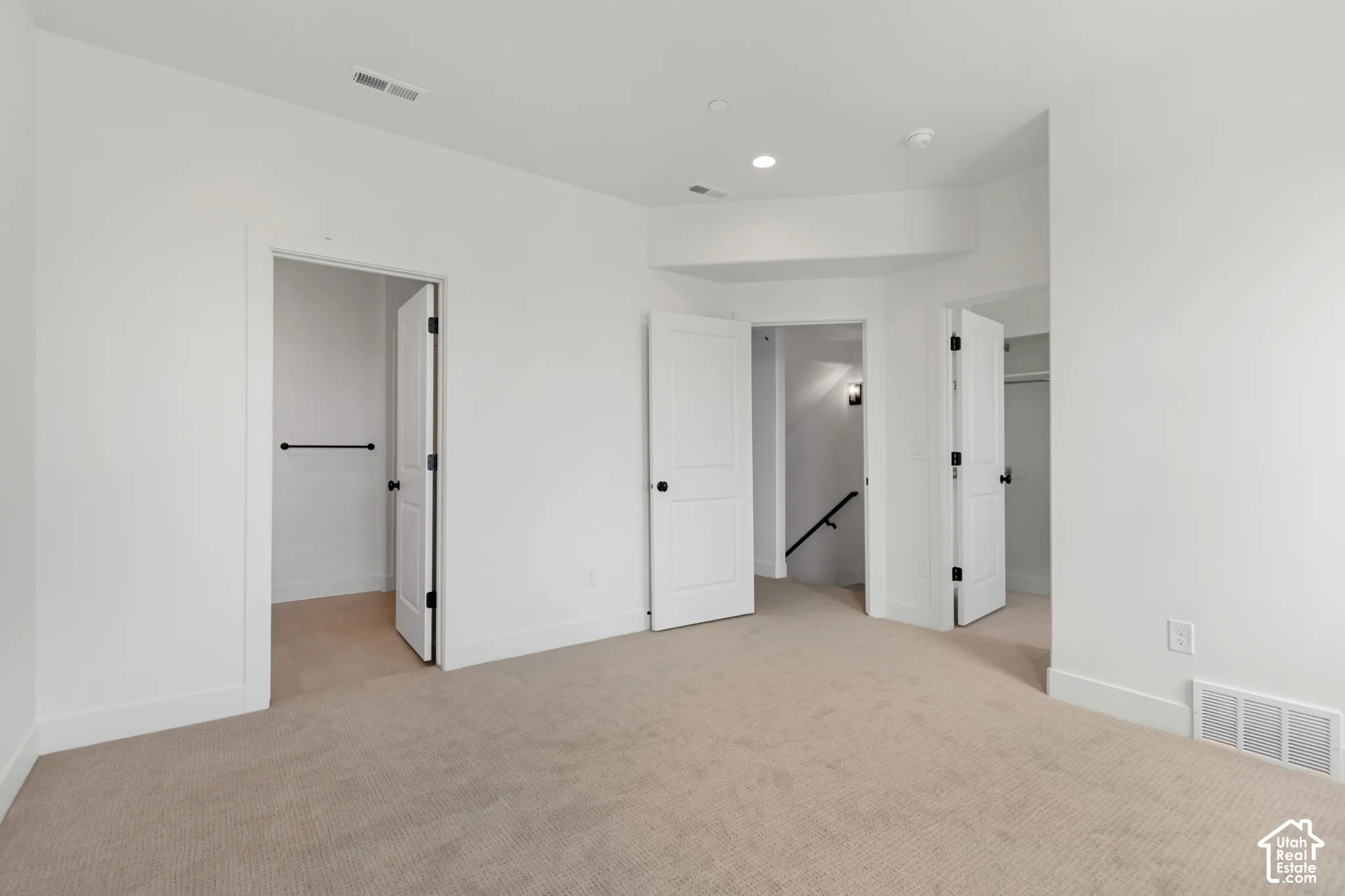 Plush carpeting, recessed lighting, interior doors with matte black hardware, and an open closet