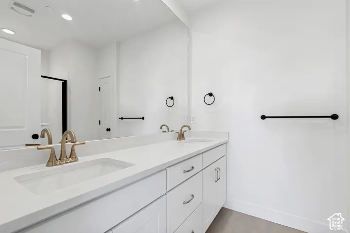 Dual integrated sinks set in a white countertop, with coordinating white cabinetry and gold-tone fixtures
