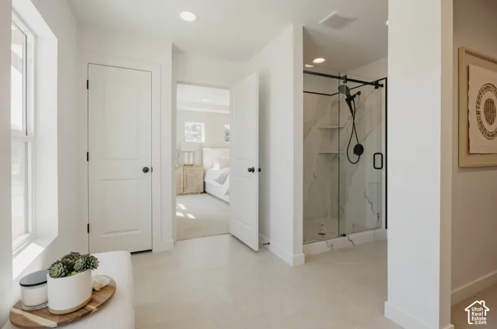 Spacious floor-to-ceiling tiled shower with a glass enclosure and matte black fixtures