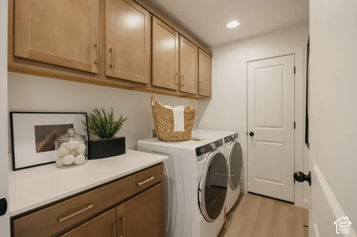 Laundry area featuring light wood-finish cabinetry, white countertop, and light wood-finish flooring