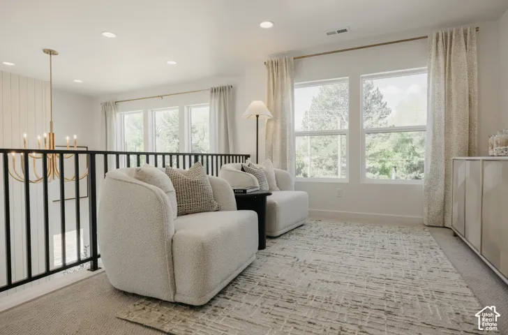 Upper-level lounge area featuring large windows, recessed lighting, a modern chandelier, and a built-in storage cabinet