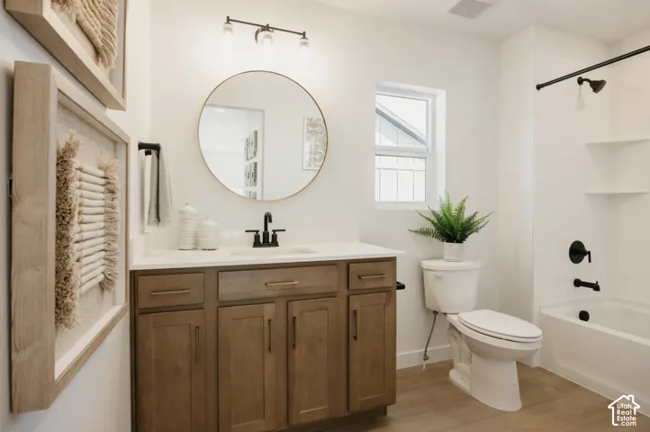 Wood-finish flooring, single vanity with wood cabinetry and white countertop, black-finish fixtures, white bathtub with a shower