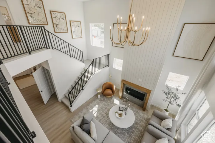 Two-story living area with high ceilings, a prominent fireplace with a wood mantle, and a multi-tiered staircase with black metal railings