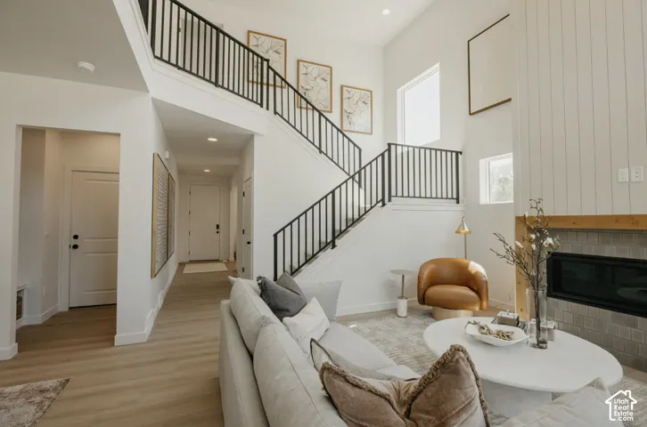 Vaulted ceilings with multiple windows, a fireplace with a wood mantel, a shiplap accent wall, and a staircase with black metal railings