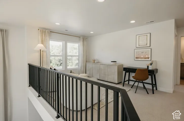 Upper level featuring carpet flooring, recessed lighting, white walls, and a black metal railing