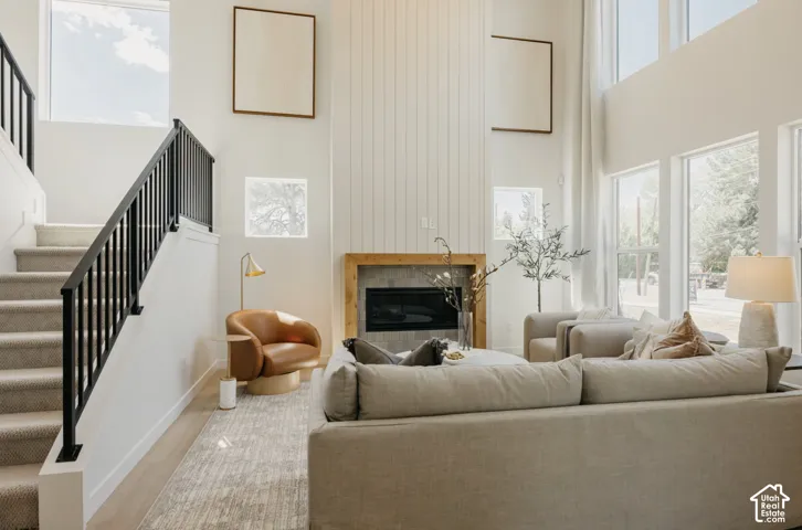 Two-story living area featuring a fireplace with a wood mantel and stone surround, a shiplap accent wall, and wood-finish flooring