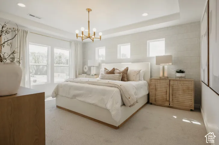 Recessed lighting, a tray ceiling, and a prominent gold-finish chandelier illuminate the carpeted flooring