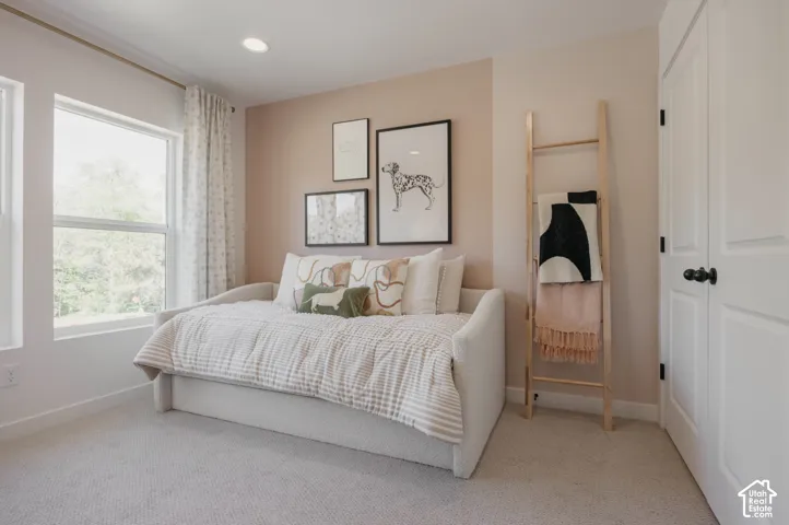 Recessed lighting, light-toned carpeting, and a large window with white trim