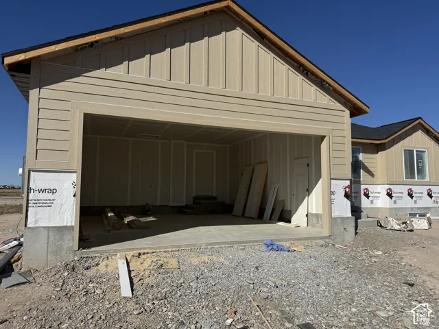 Attached garage with concrete flooring, board and batten siding, horizontal siding, and a dark shingle roof