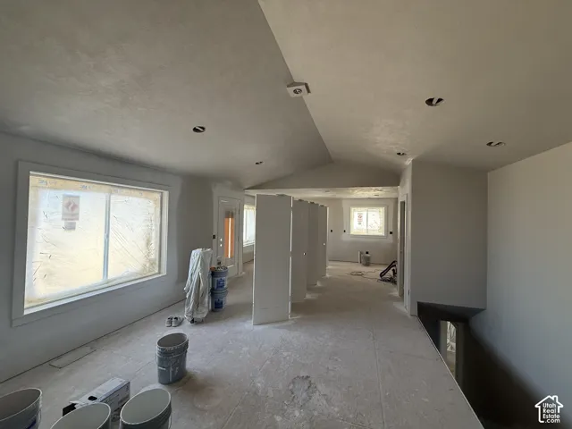Multiple windows, recessed lighting, vaulted ceiling, white interior doors, and a neutral color palette