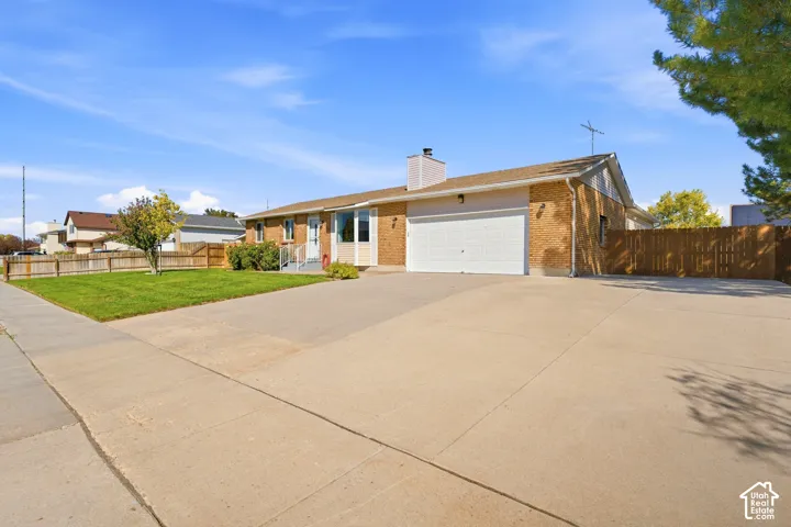 Brick exterior, attached garage, concrete driveway, front lawn, wood fencing
