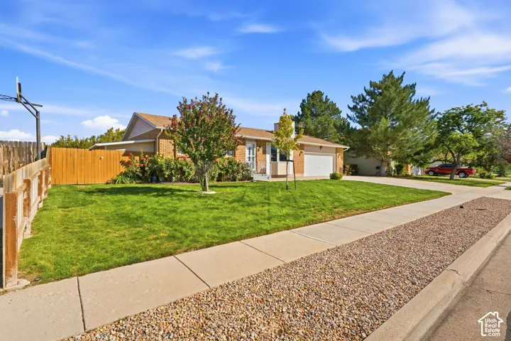Single-story brick exterior, attached garage, well-maintained lawn, privacy fencing, and established landscaping