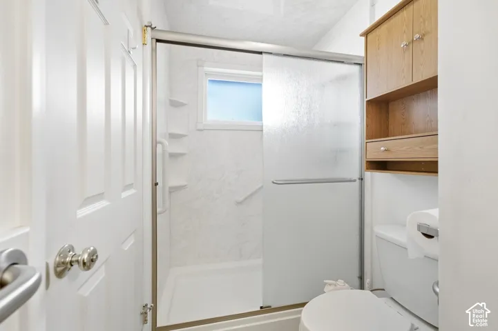 Walk-in shower with a sliding glass door and an integrated window