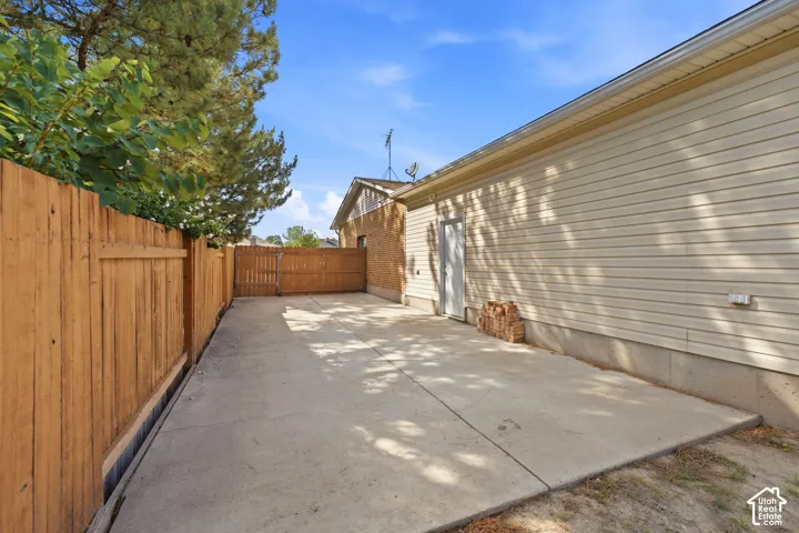 Concrete driveway with wood fencing and a gate, featuring vinyl siding