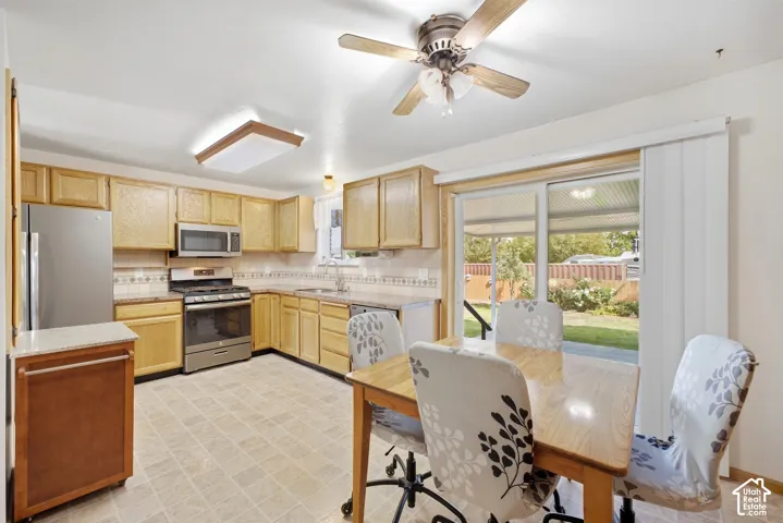 Kitchen with light wood-finish cabinetry, stainless steel appliances, and a tile backsplash