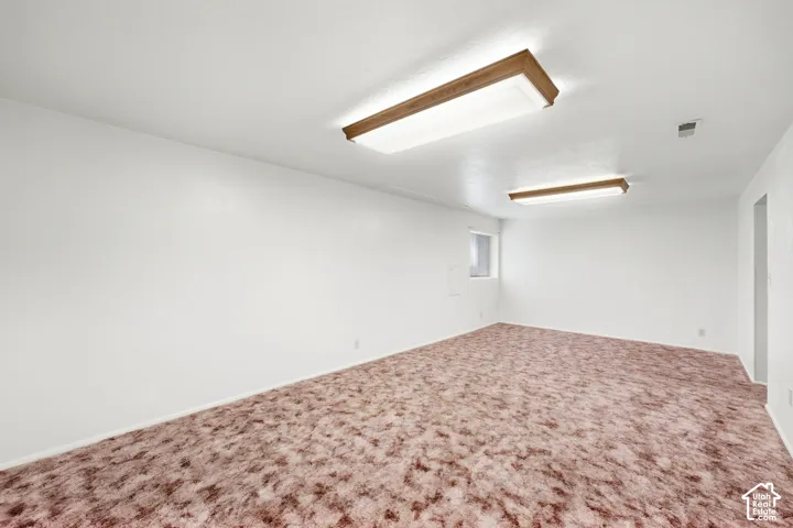 Spacious room featuring flush-mount fluorescent lighting and a high window