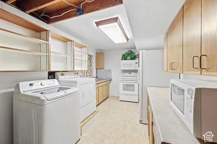 Laundry area featuring a top-load washer, front-load dryer, built-in shelving, and light wood-finish cabinetry