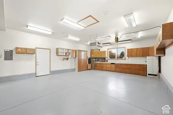 Spacious garage featuring a durable epoxy floor, extensive built-in cabinetry, an integrated workbench, and multiple overhead light fixtures