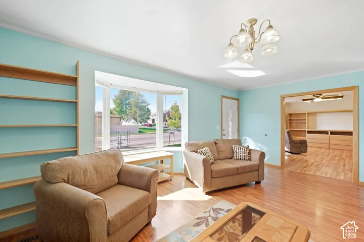 Bay window, wood-finish flooring, built-in shelving, decorative overhead lighting, and an open doorway to an additional room