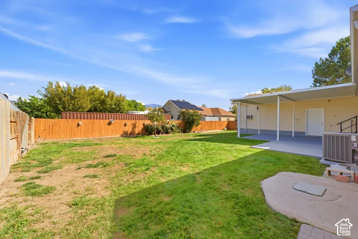 Expansive backyard featuring a wood fence, a covered patio, and a grass lawn